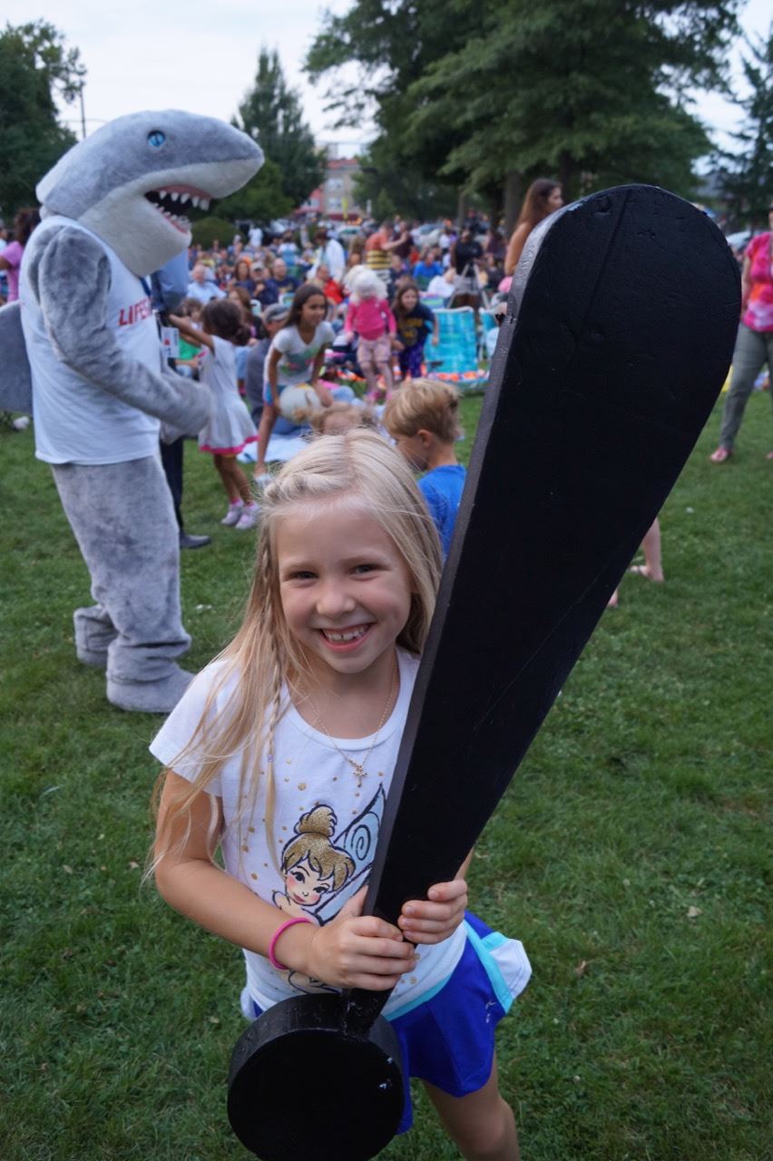 Little girl holds the Share the Fun exclamation point.